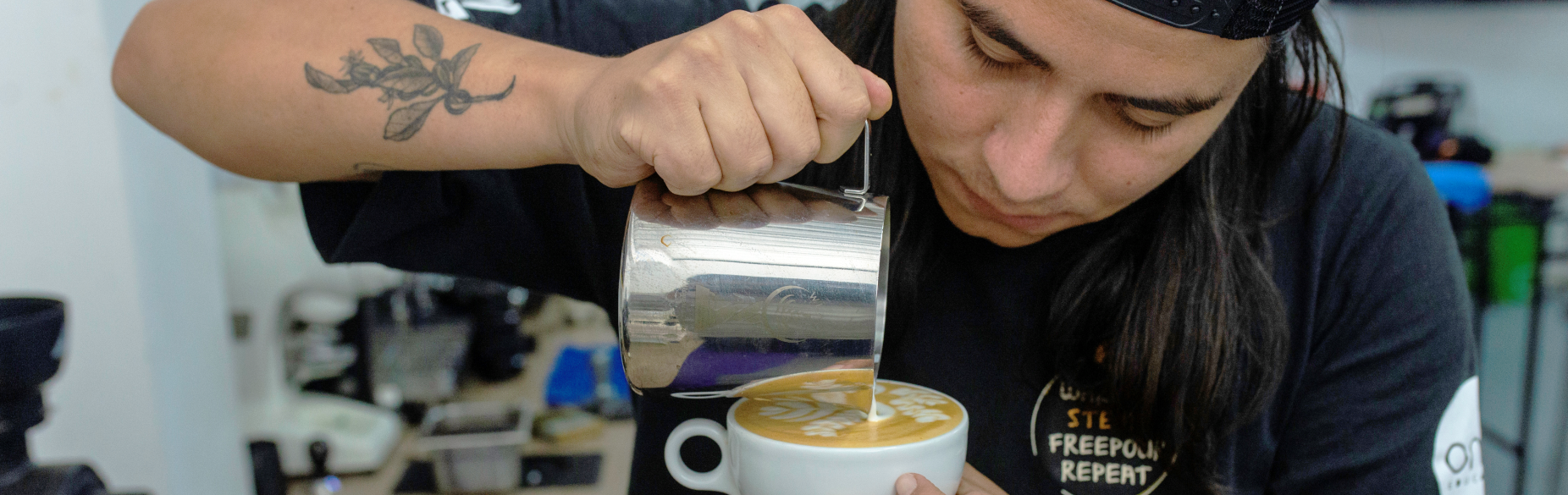 Barista vertiendo leche texturizada para dibujar arte latte en una taza