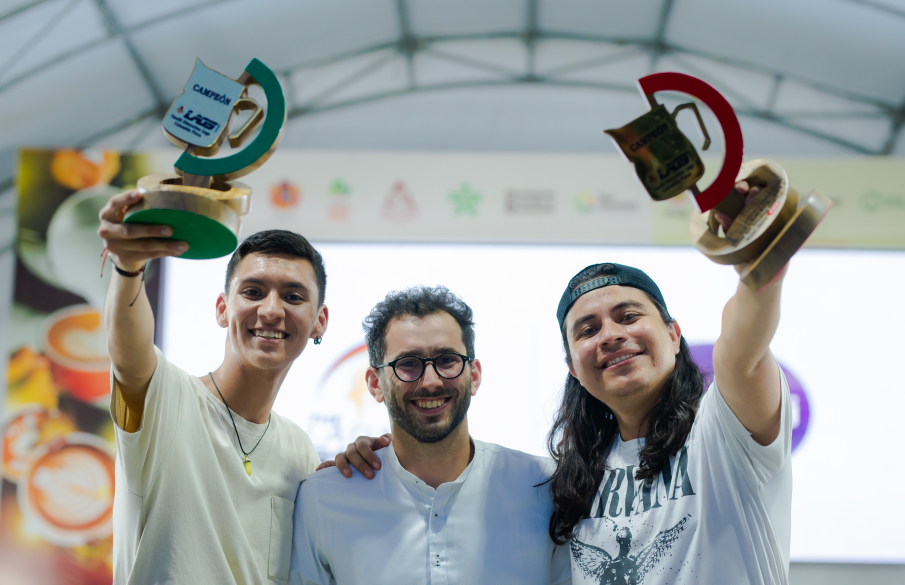 Tres ganadores sonrientes levantan sus trofeos